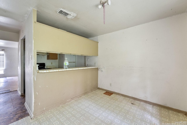 kitchen featuring light floors, visible vents, and baseboards