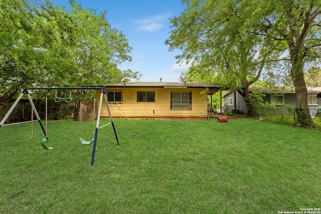 rear view of house featuring a fenced backyard, a playground, and a lawn