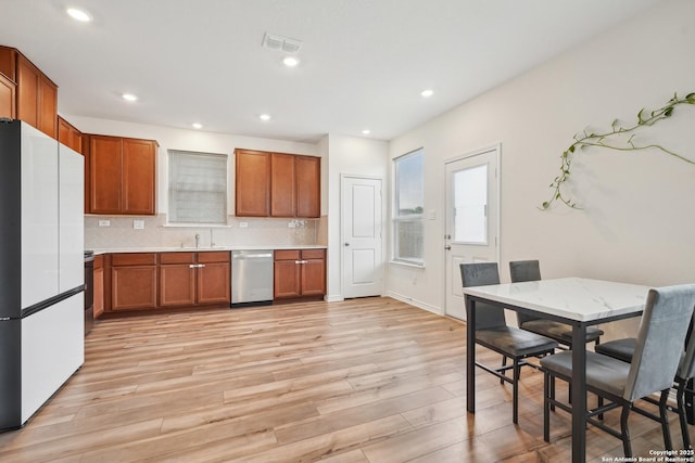 kitchen with light wood-style floors, light countertops, dishwasher, freestanding refrigerator, and visible vents