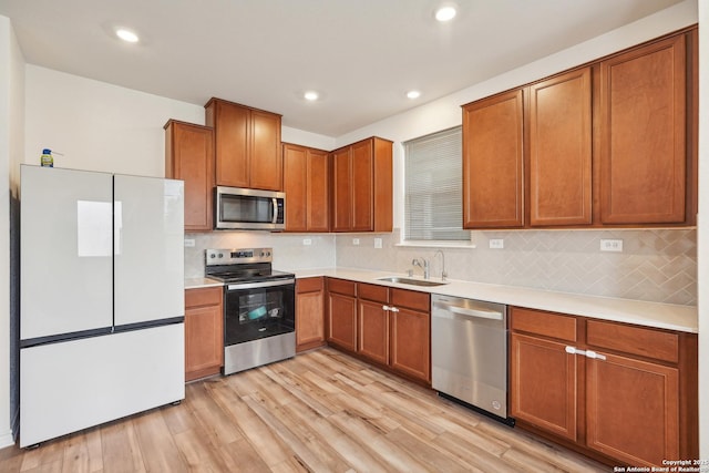 kitchen with light wood-style floors, a sink, backsplash, and stainless steel appliances