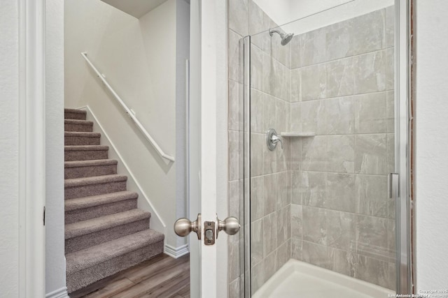 bathroom with baseboards, a shower stall, and wood finished floors