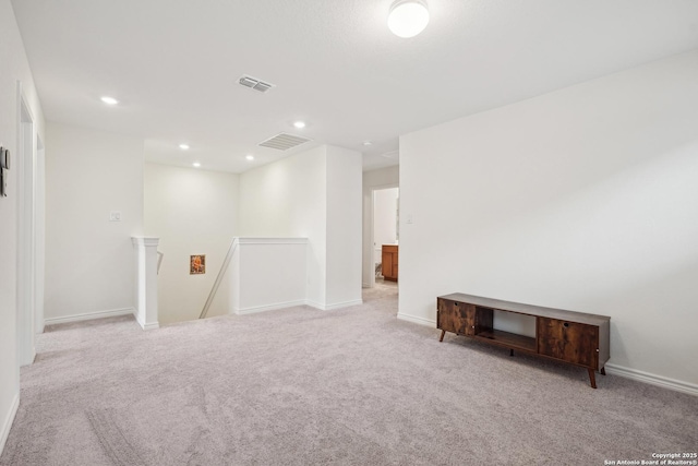 below grade area featuring baseboards, light carpet, and visible vents