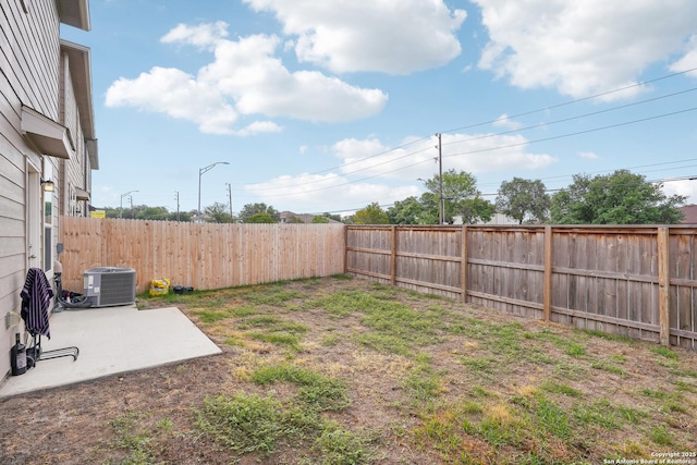 view of yard with central AC unit, a patio area, and a fenced backyard