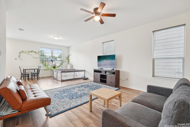 living area with visible vents, a ceiling fan, baseboards, and wood finished floors