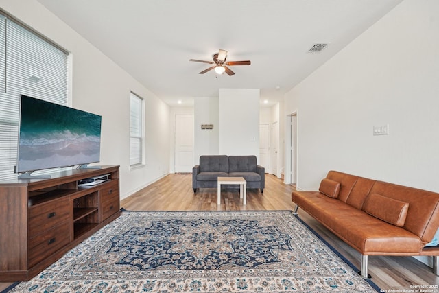 living room featuring visible vents, a ceiling fan, baseboards, and light wood-type flooring