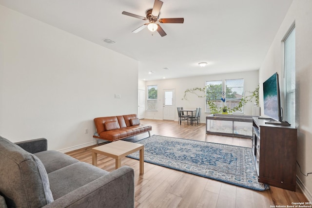 living area featuring a ceiling fan, baseboards, visible vents, and wood finished floors
