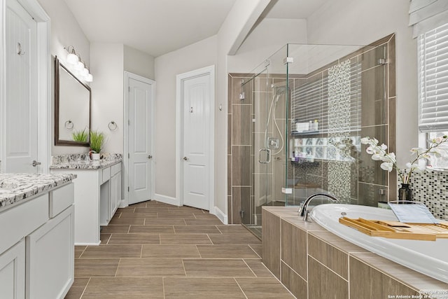 full bathroom featuring vanity, a bath, a shower stall, and baseboards
