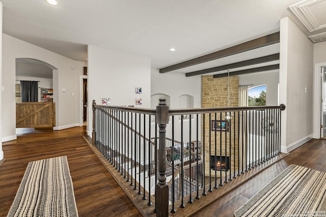 corridor with attic access, beamed ceiling, wood finished floors, and baseboards