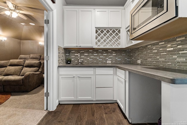 kitchen with white cabinetry, dark countertops, dark wood-type flooring, and stainless steel microwave