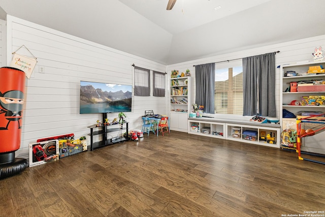 game room with a ceiling fan, wood walls, vaulted ceiling, and wood finished floors