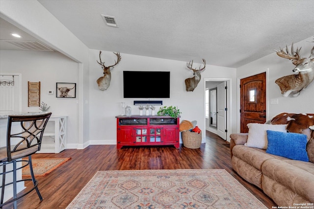 living area with baseboards, visible vents, and wood finished floors
