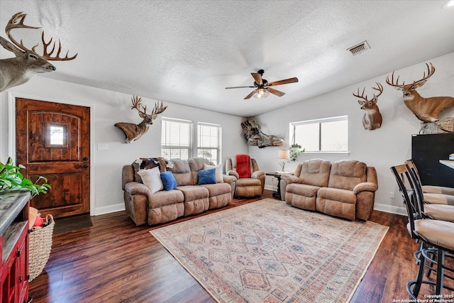 living area featuring a ceiling fan, dark wood-style flooring, and a textured ceiling