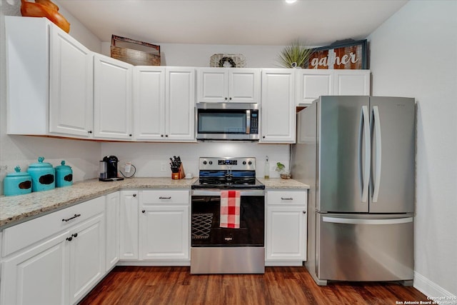 kitchen featuring light stone counters, white cabinets, appliances with stainless steel finishes, and dark wood-type flooring
