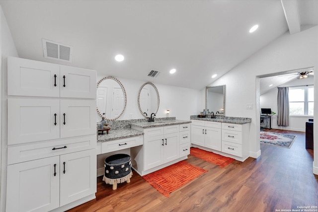 kitchen featuring white cabinetry, visible vents, lofted ceiling with beams, and a sink