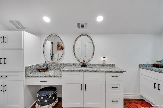 full bath with visible vents, two vanities, and a sink