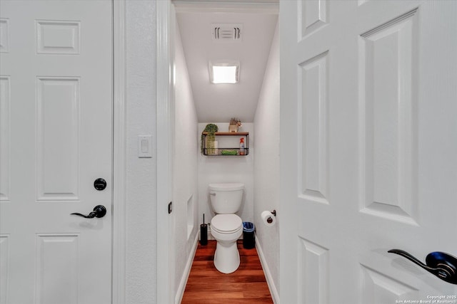 bathroom with baseboards, visible vents, wood finished floors, and toilet