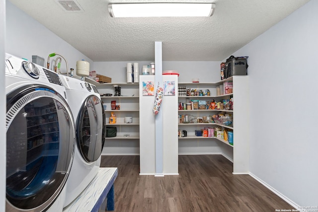 washroom with a textured ceiling, independent washer and dryer, visible vents, wood finished floors, and laundry area