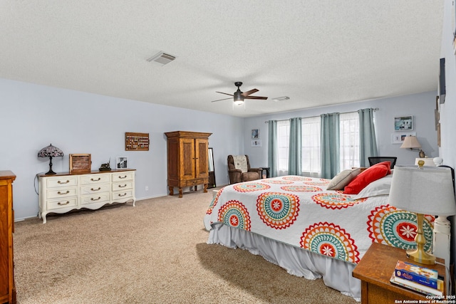 carpeted bedroom featuring a textured ceiling, visible vents, and a ceiling fan