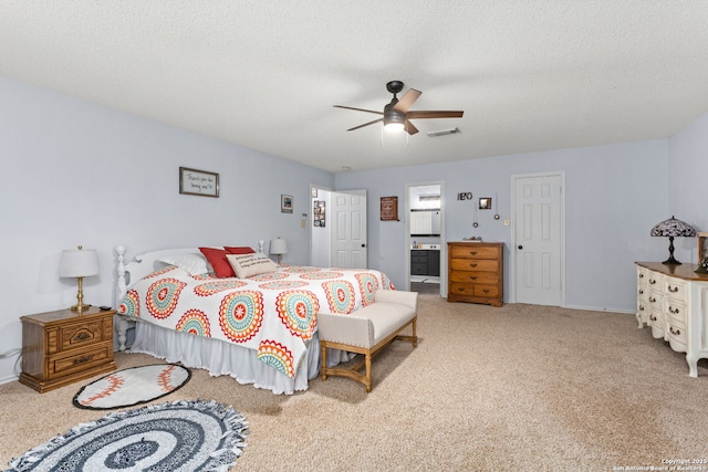 carpeted bedroom with a textured ceiling, visible vents, baseboards, a ceiling fan, and ensuite bath