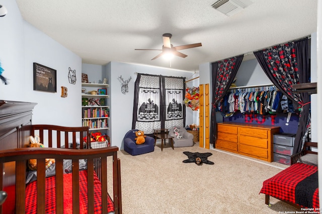 carpeted bedroom featuring a textured ceiling, visible vents, and ceiling fan