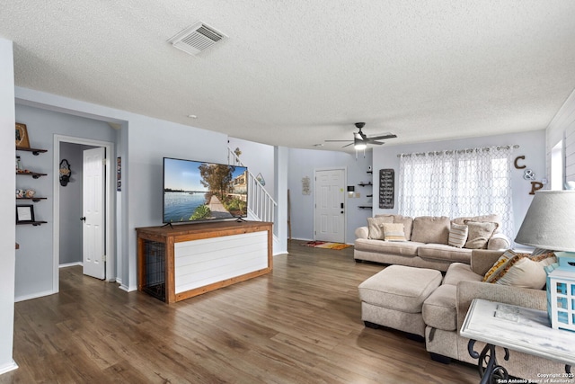 living area with a textured ceiling, visible vents, wood finished floors, and stairs