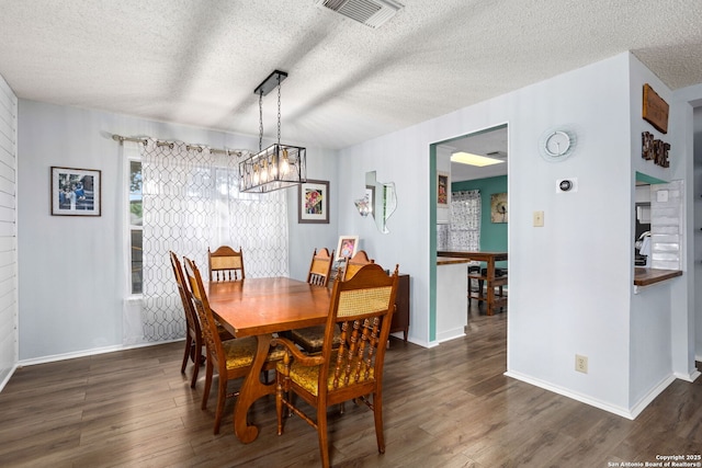 dining area with dark wood finished floors, visible vents, and baseboards