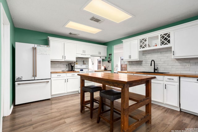 kitchen with open shelves, a sink, visible vents, butcher block counters, and white appliances