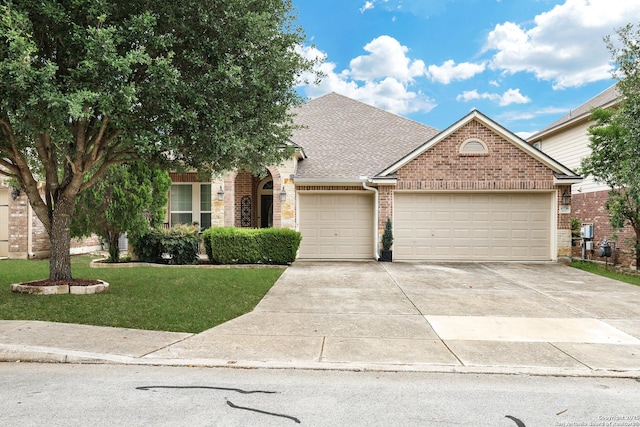 view of front of house featuring a front yard, brick siding, a shingled roof, an attached garage, and driveway