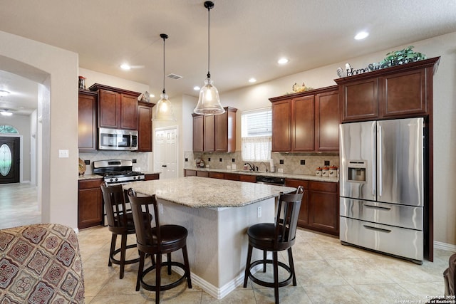 kitchen with a kitchen bar, a center island, light tile patterned floors, a sink, and stainless steel appliances