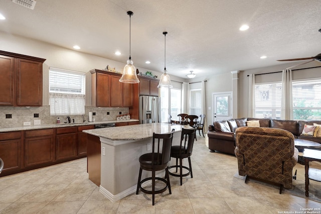 kitchen featuring stainless steel fridge, tasteful backsplash, visible vents, and a healthy amount of sunlight