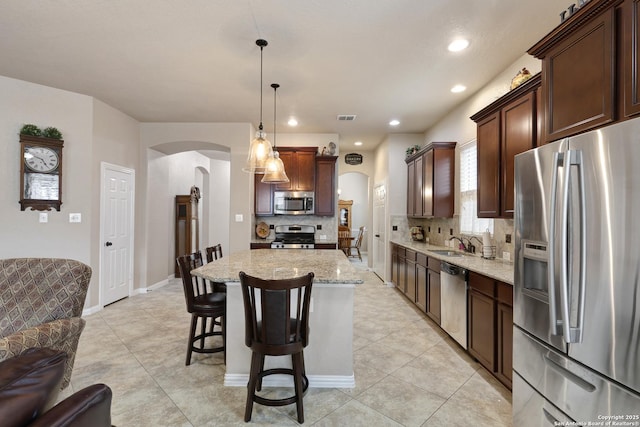 kitchen with decorative backsplash, visible vents, appliances with stainless steel finishes, arched walkways, and light stone counters