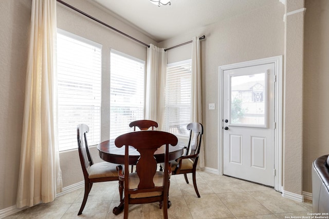 dining area featuring baseboards, light tile patterned floors, and a wealth of natural light