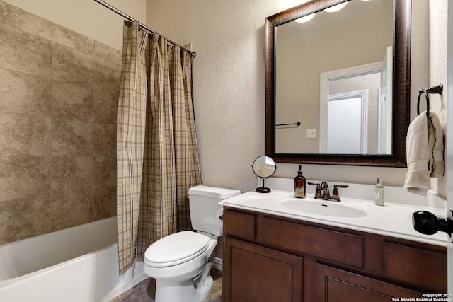 bathroom with vanity, a textured wall, shower / bath combo, and toilet