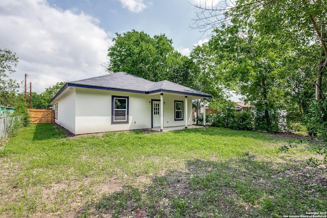 back of property featuring a yard, stucco siding, and fence