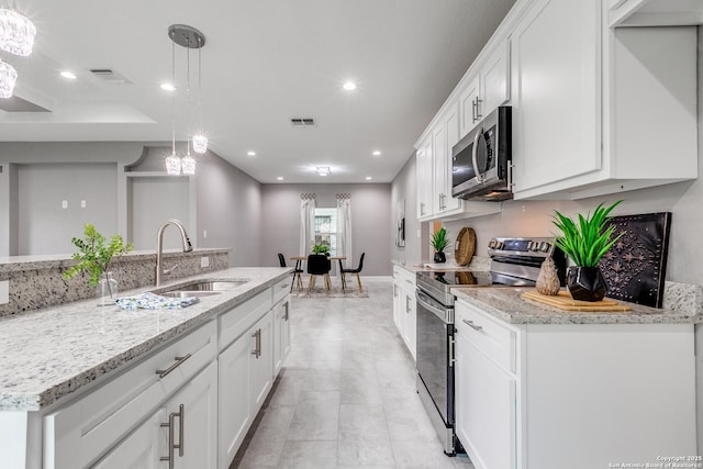 kitchen with light stone counters, appliances with stainless steel finishes, a sink, white cabinetry, and visible vents