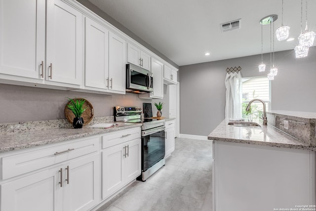 kitchen with hanging light fixtures, stainless steel appliances, white cabinets, a sink, and visible vents