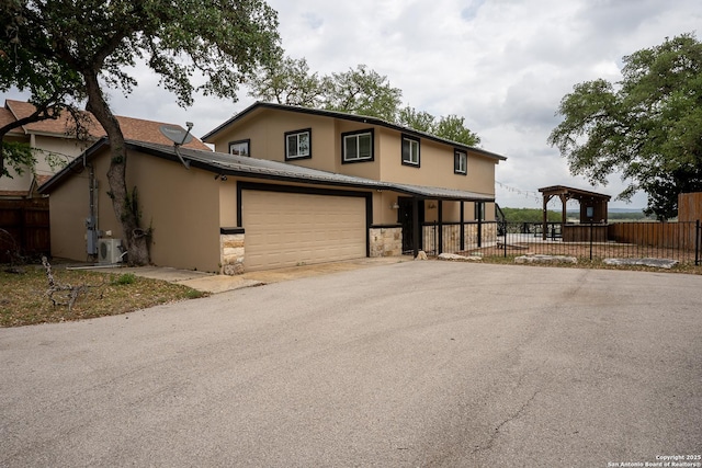 view of front of home featuring aphalt driveway, stucco siding, stone siding, and fence