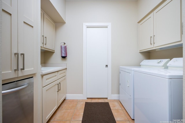 clothes washing area featuring cabinet space, light tile patterned flooring, baseboards, and washing machine and dryer