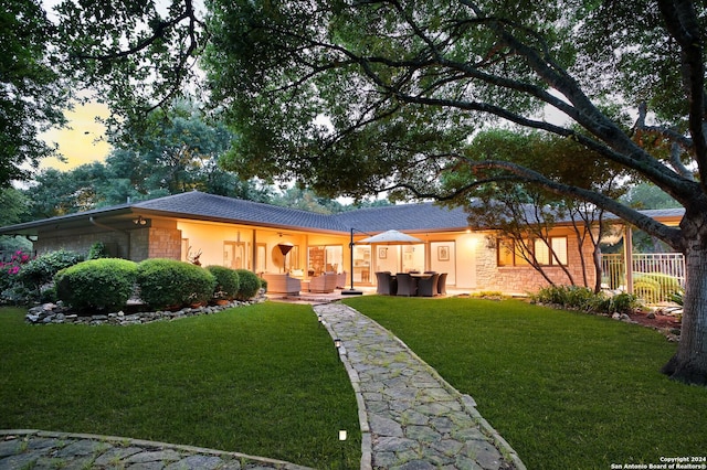 rear view of property with a lawn, fence, stone siding, and stucco siding