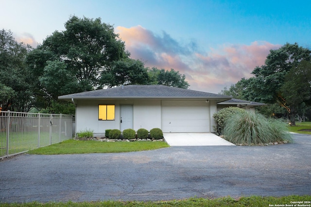 view of front facade with fence, aphalt driveway, a yard, an attached garage, and stucco siding