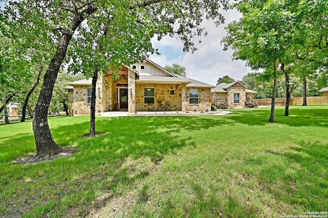 view of front of property featuring a patio, a front lawn, fence, and stone siding