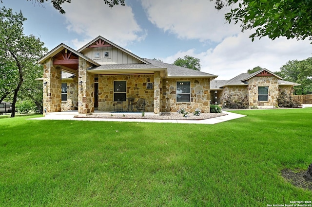 craftsman-style home with board and batten siding, a front yard, roof with shingles, a patio, and stone siding