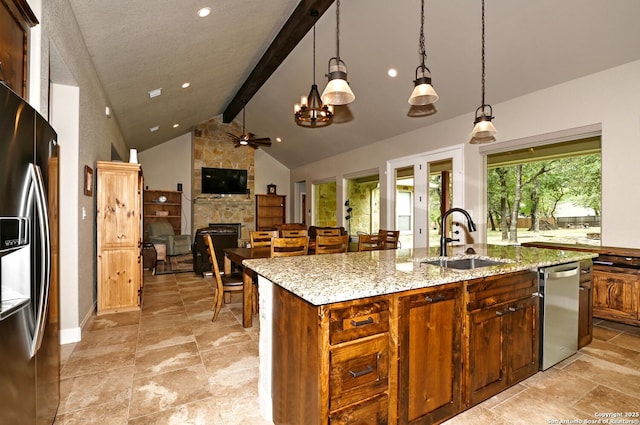 kitchen with a fireplace, beam ceiling, a sink, stainless steel appliances, and an island with sink