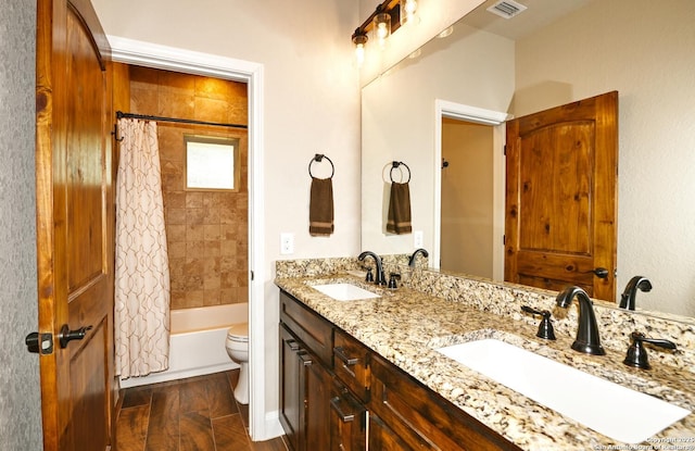 full bathroom with a sink, toilet, double vanity, and visible vents
