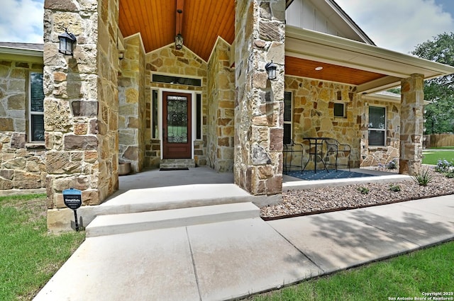 entrance to property with board and batten siding, a porch, and stone siding