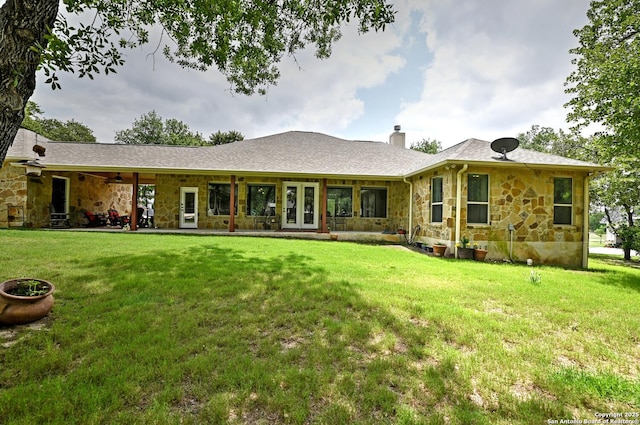 rear view of house featuring a chimney, a yard, and stone siding