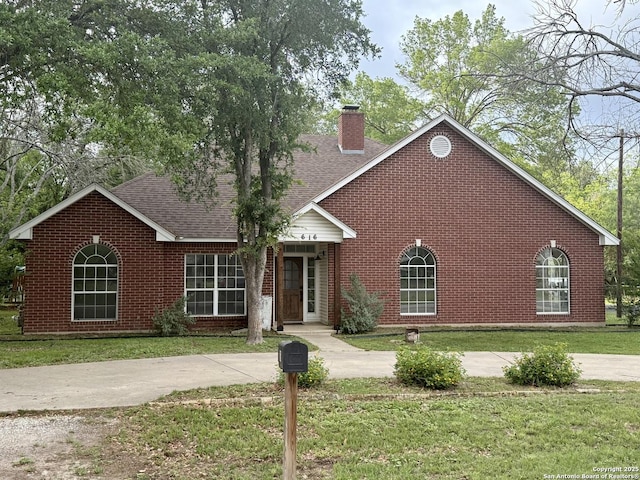 view of front of home featuring brick siding, a front yard, and a chimney