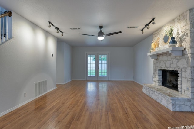 2215 Shady Rock Cir, San Antonio, TX 78231 - unfurnished living room featuring rail lighting, wood finished floors, ceiling fan, and a stone fireplace