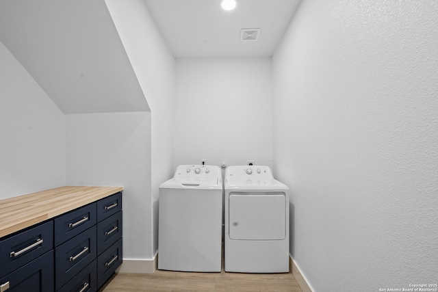 1050 Trail Pass Dr, Canyon Lake, TX 78133 - laundry room with visible vents, baseboards, cabinet space, washing machine and clothes dryer, and light wood-style flooring