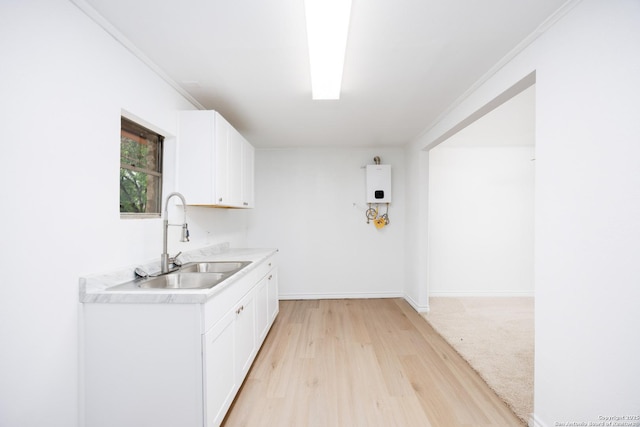 kitchen with white cabinets, a sink, light countertops, light wood-style flooring, and water heater